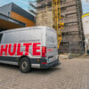 Schulte Bauunternehmen Servicefahrzeug vor Baustelle mit Kran und eingerüstetem Gebäude